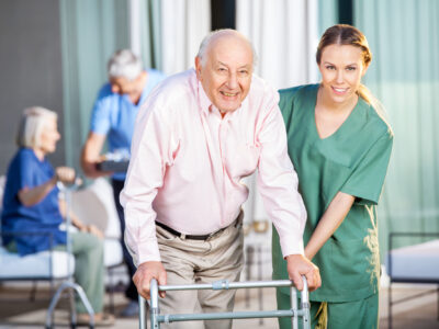 Common Mistakes To Avoid In A Nursing Home Abuse Case - Female Caretaker Helping Senior Man In Using Zimmer Frame